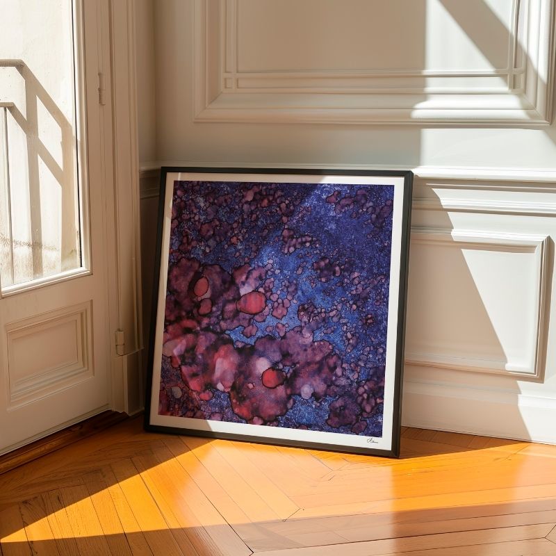 Abstract painting of purple and blue, leaning against a white wall on a wooden floor near a window with sun shining in